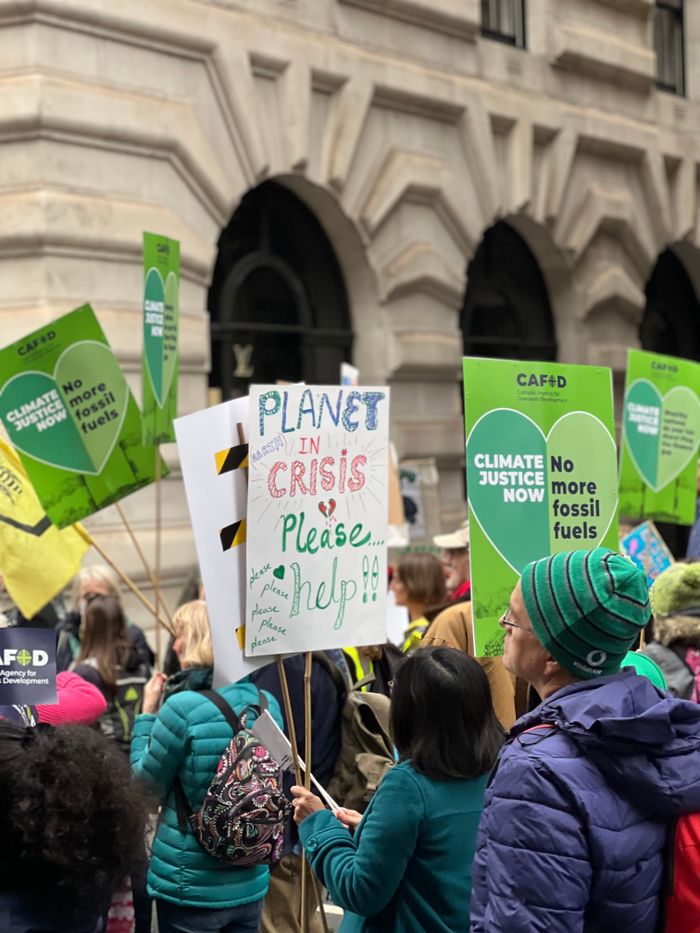 Crowd of protesters advocating for climate awareness with signs indoors.
