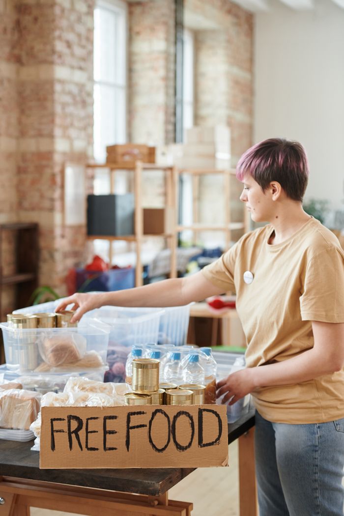 A volunteer organizes free food donations in an indoor community center setting.